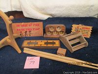 Photo showing a variety of wooden items on a dark blue surface including a wooden multi-photo frame, crib board, drum sticks, rolling pin, a small wooden seat, a small block, and a fire instruction sign.