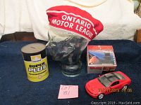 Four items including a glass cup holder with red Ontario Motor League felt cover, Petro Canada Super Plus oil can bank, and red metal GT Mustang model car