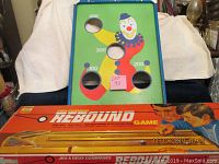 Photo showing bean bag toss game board with clown and point holes, with Rebound game box in front