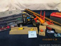 MegaToyBrand hauler transporter truck with doors open showing die-cast cars inside, plastic car ramps and toy accessories laid out next to it.