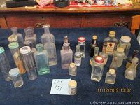 Photo showing the full collection of 22 glass bottles varying in shapes and sizes from 1.5 to 6.5 inches tall, arranged on a dark fabric surface