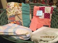 Vintage woven green basket filled with the unfinished quilts and bags of yarn, showing contents clearly