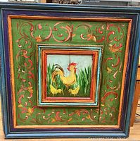 Full front photo showing the large square frame with vivid painted folk art style decoration of a rooster and chicks central panel surrounded by green with scrollwork.