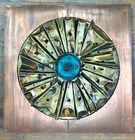 Full front image showing the square copper wall art with circular folded centerpiece and blue-green patina.