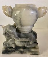 Front view of the solid marble elephant sculpture holding an urn with decorative handles, showing overall design and condition.