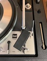 Close-up of tonearm, cartridge, and controls with branding and speed options visible