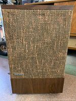 Front angle view of Bose 501 speaker showing cloth cover and wooden bottom panel.