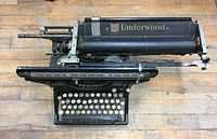 Top view of black Underwood typewriter on wooden surface showing keys and carriage.