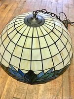Photo of stained glass dome-shaped fixture from top at side showing cream colored glass and hanging chain.