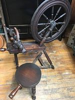 Vintage wooden spinning wheel highlighting dragon head and wheel assembly on wooden floor.