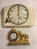 Two clocks shown side by side: Diehl wall clock with key and Landex Royal Craft Japan gold-tone clock with horse decoration