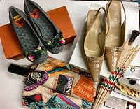 Two pairs of women's shoes, two umbrellas, scarf, compact mirror, and makeup case displayed on a white surface.