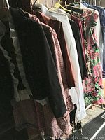 Side view of coats and dresses hanging on rack showing texture and color variety
