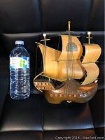 Full view of vintage model sailboat with water bottle for scale, showing size roughly 12 inches tall.