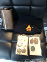 Three main objects: metal war tin flask, black legion hat with embroidered insignia, and two sets of Boy Scout badges and pins mounted on cards