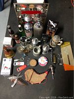 Full lot overview showing assorted bottles, glasses, steins, and bar accessories arranged on floor.