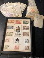 Framed display panel showing complete 13-piece 1967 Canadian Centennial issue stamp set with various denominations and designs.