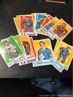 Photo showing 10 vintage hockey cards spread out, featuring players from teams including Toronto Maple Leafs, L.A. Kings, Montreal Canadiens, St. Louis Blues, and Boston Bruins with colorful card backgrounds.