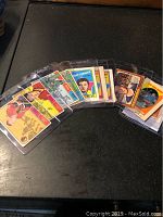 A photo showing a spread of 11 vintage hockey cards protected in plastic sleeves on a dark surface.