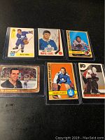 Photo showing 6 vintage hockey cards in plastic sleeves on a dark surface. Players identified on cards are Barry Cullen, Brit Selby (signed), Tony Esposito, Ed Giacomin, Jacques Plante, and Pelle Lindbergh.