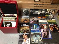 Open red ottoman containing vinyl records in sleeves, some covers visible