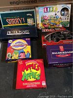 Photo showing the 7 game boxes stacked, including Sorry!, The Game of Life, Risk, Pictionary, Cranium, Apples to Apples, and Balderdash.