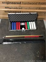 Pool cue and its soft black carrying case laid out on floor with poker chip case behind.