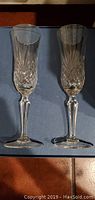 Two full lead crystal champagne flutes with intricate cut design, glassware closeup view.