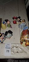 Wide view showing all Disney character figurines and the ceramic coin bank house on a table.