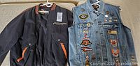 Two Harley Davidson jackets on a hanger: a black varsity jacket and a denim cut jacket with many patches and pins.
