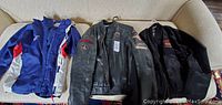 Three jackets laid out on a couch showing all items in the lot