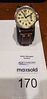 Front view of Luminox wristwatch on leather strap atop auction paper showing lot number