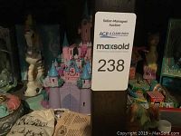 Photo showing shelf with Disney castle, seahorse figurine, angel figurine, and other collectibles