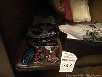 Photo showing multiple Harley Davidson patches, folded bandana, and bag corner in a dark setting.