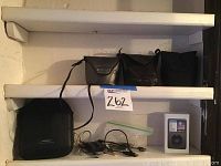 Shelf with two leather camera cases, Bose headphone case, cables and iPod box.