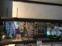 Wide shot of baseball cards displayed behind glass with three baseballs and the Baseball Encyclopedia book visible.