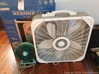 Three fans shown: white and gray Lasko 20 inch Weather-Shield box fan with original box behind, white Lakewood 20 inch box fan beside a teal plastic small vintage desk fan; all fans show some dust and dirt except Lasko which appears cleaner.