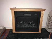 Front view of the electric fireplace showing the wood mantel and black firebox with embers inside.