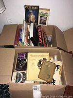 Two large boxes full of books showing a variety of titles including "Cruel Shoes," a dictionary, and others.