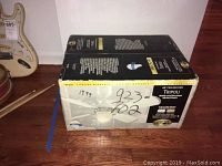 Box of Hampton Bay Tripoli 48 inch ceiling fan with pricing and lot stickers visible.