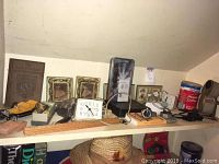 Shelf with vintage clocks, watches, wall art, thermometers, and other items including a wooden ruler and framed photos.
