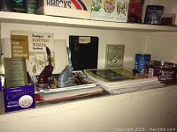 Vintage office and sewing supplies arranged on a shelf with tins, manuals, and embossing stamps visible