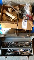 Photo of two cardboard boxes with coil rope and hardware parts, and the open metal toolbox showing hand tools inside