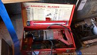 Milwaukee Sawzall reciprocating saw inside open carrying case with blade chart on lid and accessories inside.
