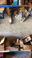 Wide shot of nine boxes containing hardware and tools arranged on shelf and floor