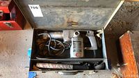Vintage Skil Rotohammer electric hammer and accessories inside metal carrying box.