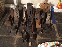 Group of nine vintage metal-bodied hand planes placed on the floor, some marked Bailey or Stanley, with wooden handles and knobs.