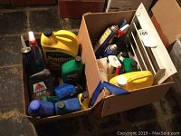 Box with assortment of automotive fluids and accessories on floor