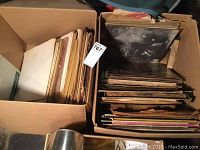 Two large boxes filled with over 60 vinyl LP records of various genres, stacked vertically and horizontally, showing worn and vintage covers.