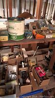 Shelf with various boxes of vintage hardware components including hinges, locks, nails, with a large Flagstar container